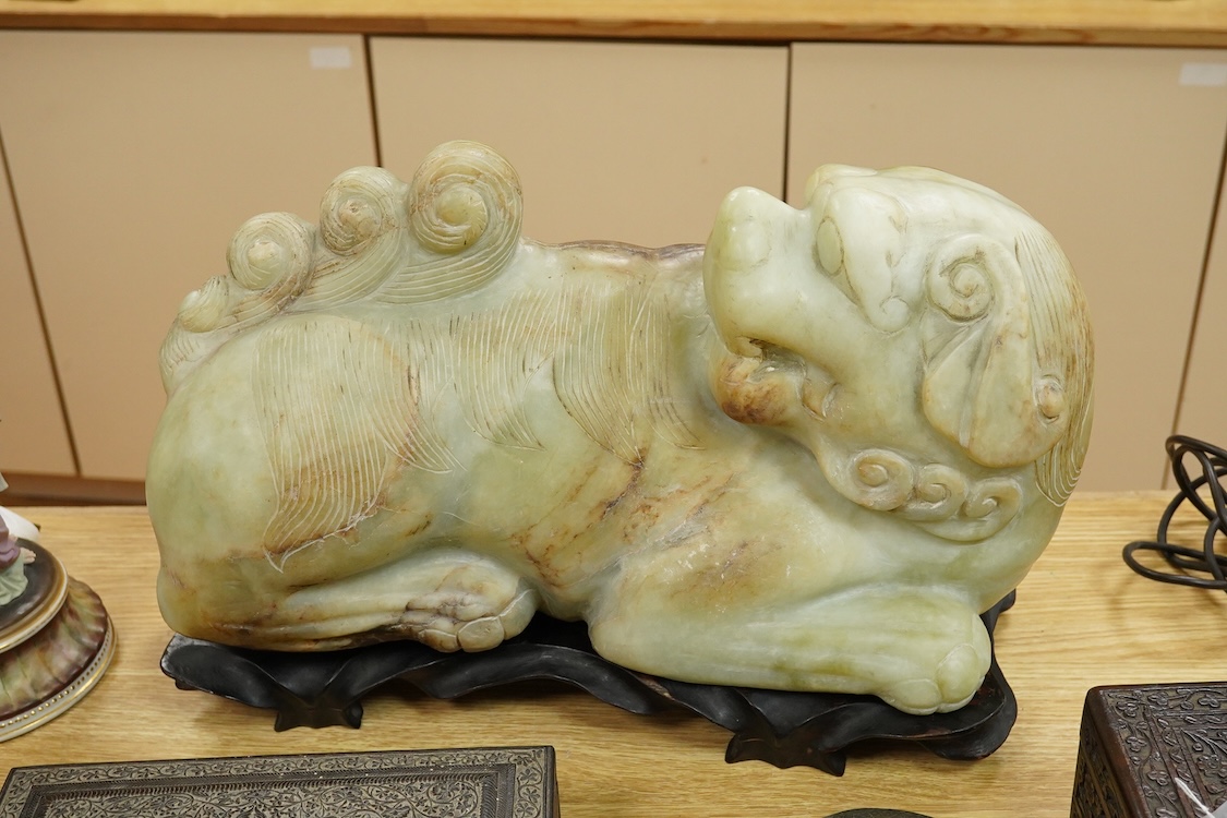 A large Chinese bowenite jade model of a lion dog, wood stand, 44cm